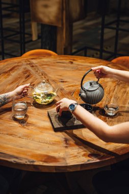 Tahta bir masada sıcak çay içen insanların seçmeli odak noktası. 