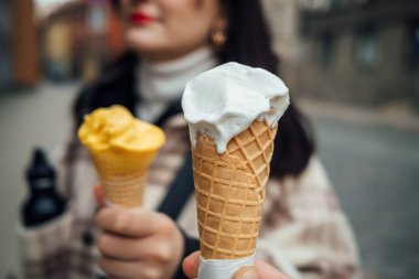 Tatlı beyaz dondurma külahlarını tutan iki kişinin yakın çekimi.