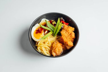 Parlak arka planda kızarmış tavuk ve yumurtalı Ramen çorbası.