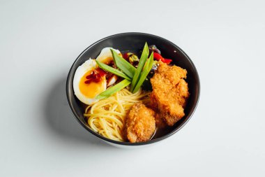 Parlak arka planda kızarmış tavuk ve yumurtalı Ramen çorbası.