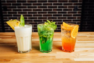 Ahşap masada farklı aklolik kokteyller, pina colada, taze mojito Aperol sprey kokteylleri, kokteyl masası..