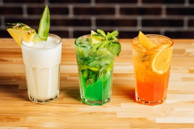 Ahşap masada farklı aklolik kokteyller, pina colada, taze mojito Aperol sprey kokteylleri, kokteyl masası..