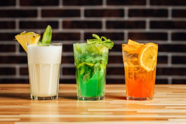 Ahşap masada farklı aklolik kokteyller, pina colada, taze mojito Aperol sprey kokteylleri, kokteyl masası..
