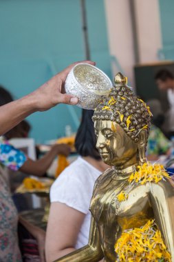 Songkran festivalinin Tayland geleneğinde Buda heykeline su dökülüyor 