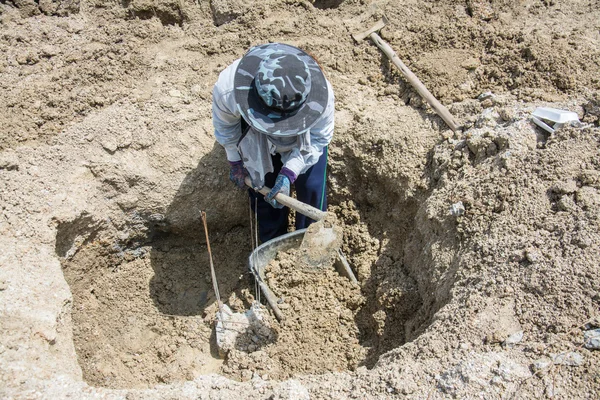 Furo de escavação do trabalhador com uma enxada no canteiro de obras — Fotografia de Stock