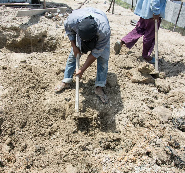 Hoyo de excavación del trabajador con una azada en el sitio de construcción —  Fotos de Stock