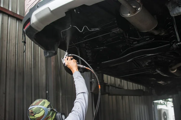 The mechanic paints  suspension carr with a paint gun.  Rust spray