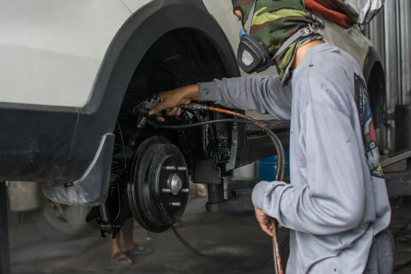 The mechanic paints  suspension carr with a paint gun.  Rust spray