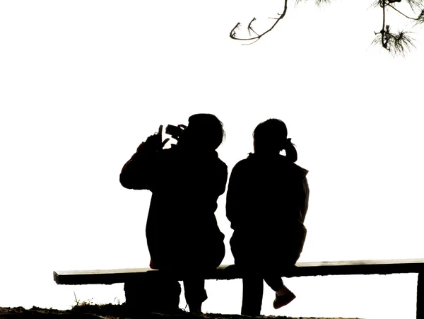 Silhouette Paar liebt es, auf Bank zu sitzen — Stockfoto