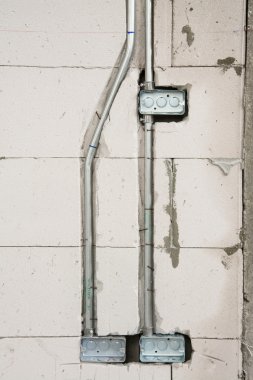 İnşaat alanındaki duvarda elektrik sistemi, demir boruları olan bir priz.