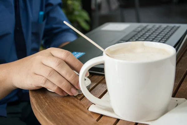 Homem com uma xícara de café trabalhando em seu laptop — Fotografia de Stock