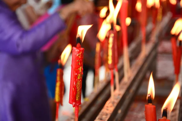 Hand cense joss stick to at an incense burne and burning candle — Stock Photo, Image
