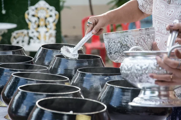 Puts food offerings in a Buddhist monk's alms bowl — Stock Photo, Image