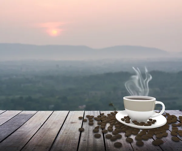 Cup with coffee on table over mountains landscape with sunrise — Stock Photo, Image