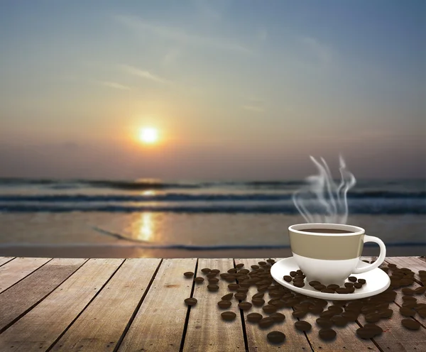 Copo com café na mesa sobre o mar ao nascer do sol — Fotografia de Stock