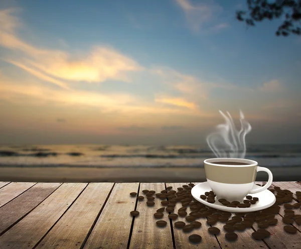 Copo com café na mesa sobre o mar ao nascer do sol — Fotografia de Stock