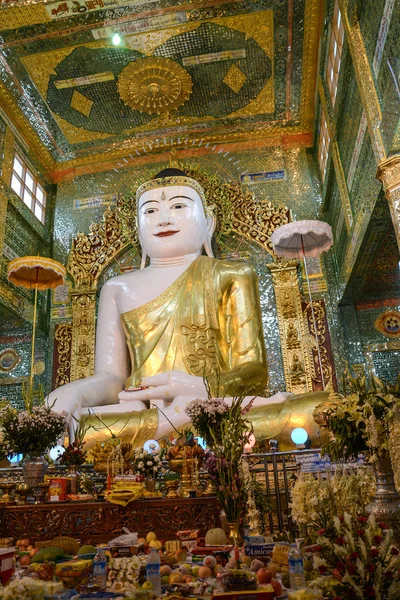 Mandalay - 31 lipca 2015: Złoty siedzący Budda urządzone z kwiatami w świątyni Sagaing Hill, podczas modlitwy wiernych na 31 lipca 2015 r. w Mandalaj, Myanmar — Zdjęcie stockowe