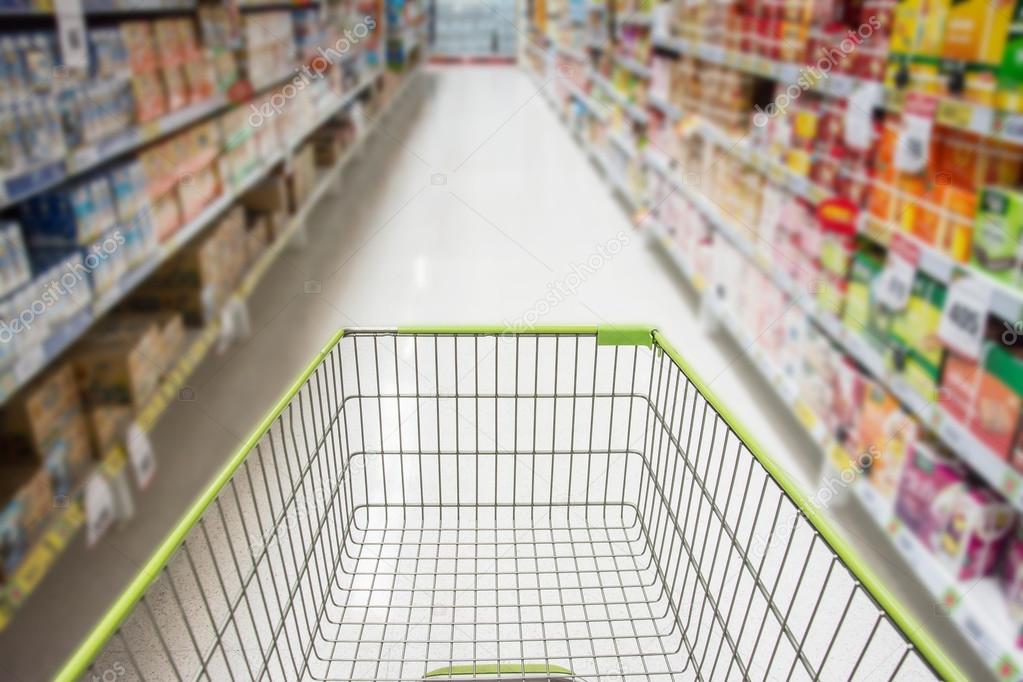 Supermarket interior, empty red shopping cart.