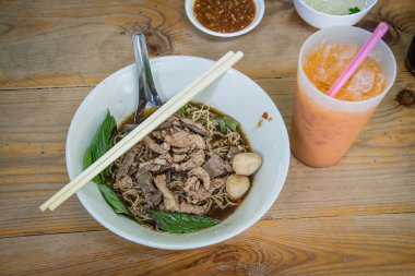 Domuz eti ve domuz eti topları ile çorba Tay tarzı ahşap masa üzerinde ile erişte