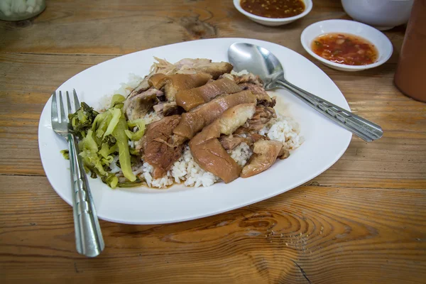饭上炖肉腿，木桌上有小碗。泰国菜 — 图库照片