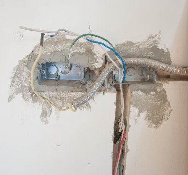 İnşaat alanındaki duvarda elektrik sistemi, demir boruları olan bir priz.