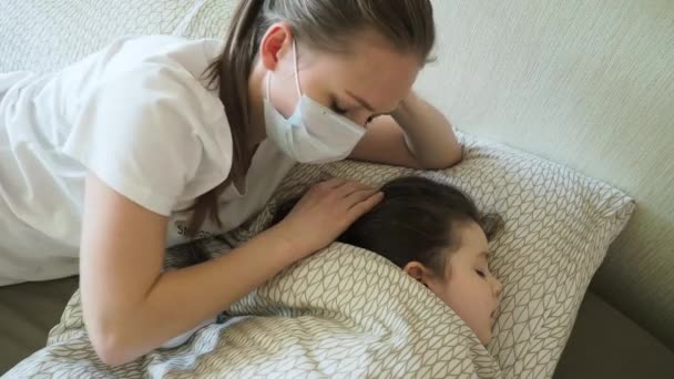 Mutter mit Maske, die den Kinderkopf berührt und die Temperatur überprüft. Coronavirus-Pandemie — Stockvideo