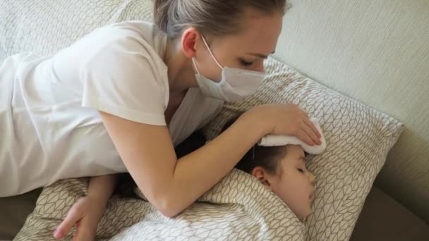 Mor med mask servetter barn panna med en fuktig handduk för att sänka temperaturen. — Stockvideo