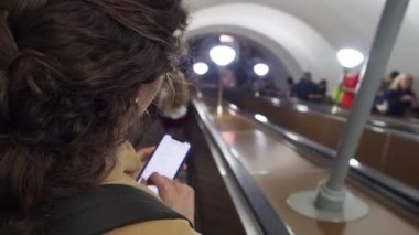 Metroda yürüyen merdivende mesaj atan ve kaldıran bir kadın. Kapat.