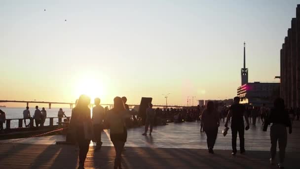 Lidé procházející se po promenádě a užívající si zlatého západu slunce. — Stock video