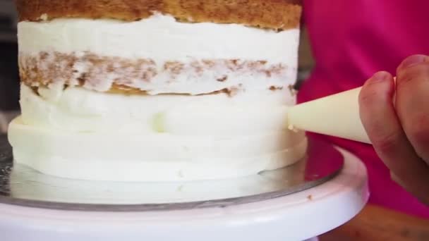 Chef piping out crème remplissage sur un gâteau éponge à l'aide d'un sac à pâtisserie. Gros plan. — Video