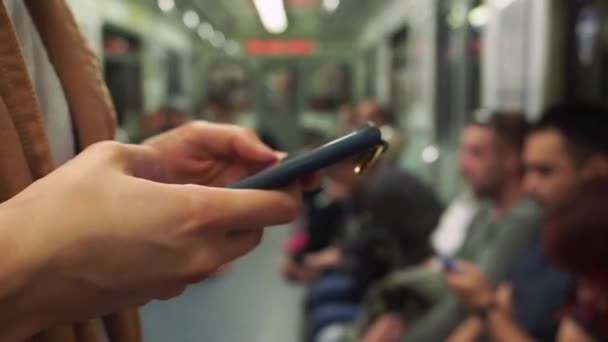 Woman texting against sitting people in the subway. Close up — Stock Video