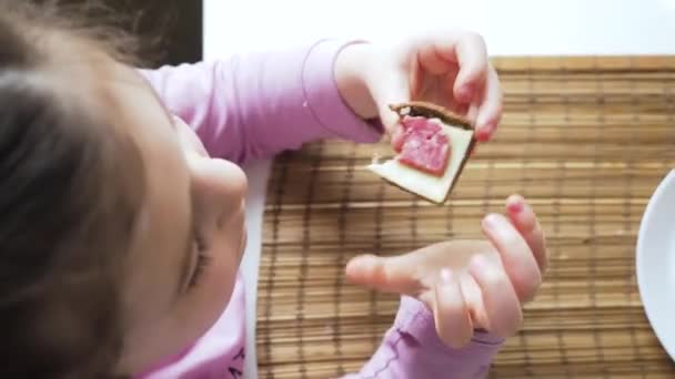 Schattig klein meisje eet graag broodjes met goede eetlust. Sluiten. — Stockvideo