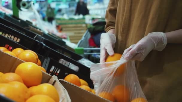 Vrouw selecteert vers oranje in latex handschoenen in de supermarkt. Vitamine C. Sluiten — Stockvideo