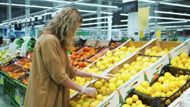 Vrouw selecteert verse citroenen in latex handschoenen in een supermarkt. Vitamine C — Stockvideo