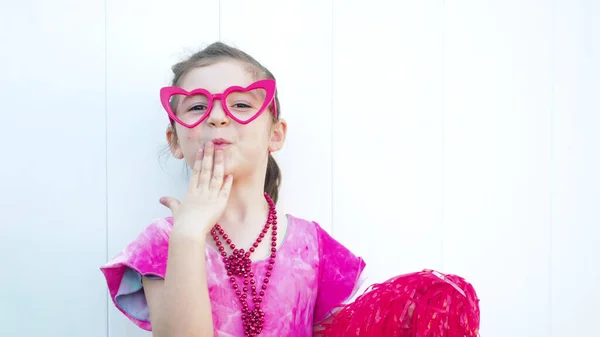 Happy dark hair girl in funny red heart glasses smiles and looks at camera. Celebrating Valentines day white background