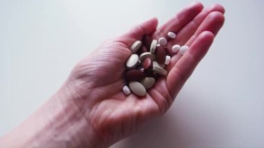 Kadın haplarla dolu elini açıyor, bazılarını seçiyor ve alıyor. Makro