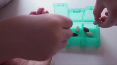 Anne hapları tutuyor ve çocuk hapları organizatöre ayırıyor. Kapat.