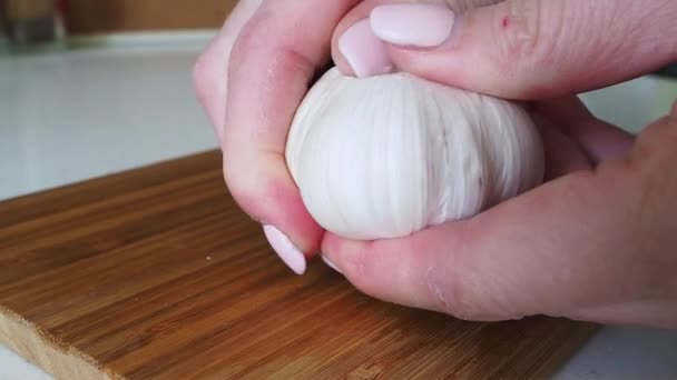 Dientes de ajo pelados femeninos en una tabla de cortar de madera para la inmunidad. De cerca. — Vídeos de Stock