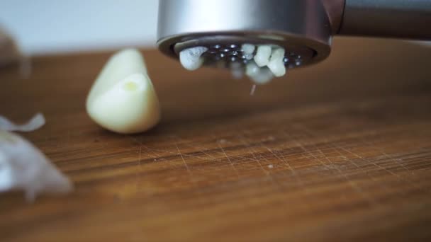 Θηλυκό θρυμματισμένο φρέσκο σκόρδο σε μεταλλικό μασέρ σε ξύλινο τραπέζι Κοντινό πλάνο — Αρχείο Βίντεο