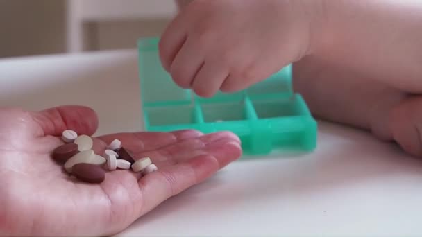 Mother holding pills and kid separates pills into the Organizer. Close up — Stock Video