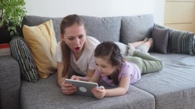 Anne ve küçük kız dijital tablet kullanıyor ve Covid-19 karantinasında şaşırtıcı.