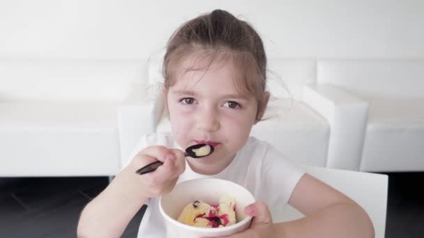 Zdrowe słodkie przedszkola ciemne włosy i brązowe oczy dziecko je lody, cieszy. Dziecięca koncepcja organiczna. Białe tło — Wideo stockowe