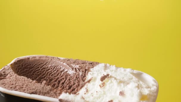 Schmelzschokolade und Vanilleeis mit moderner Schaufel aus dem Behälter schöpfen. Vorderseite gelber Hintergrund — Stockvideo
