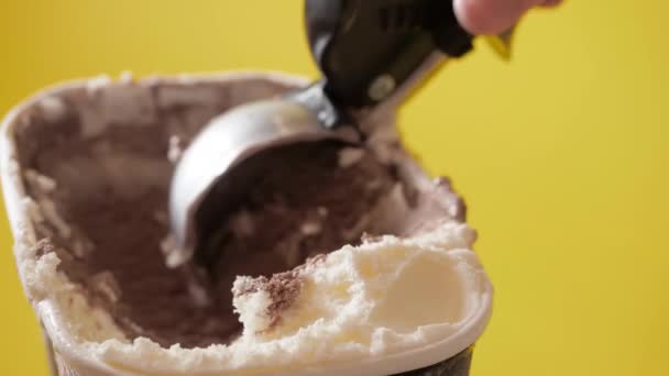Scooping λιωμένη σοκολάτα και παγωτό βανίλια από δοχείο με σύγχρονη σέσουλα. Κίτρινο φόντο. Έννοια τροφίμων — Αρχείο Βίντεο