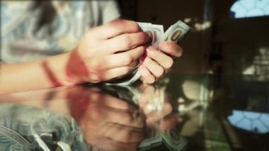 Dünya ekonomik krizi. Ev hanımı elinde 100 dolarlık banknotlar tutuyor ve Amerikan nakitlerini sayıyor. Yakın çekim.