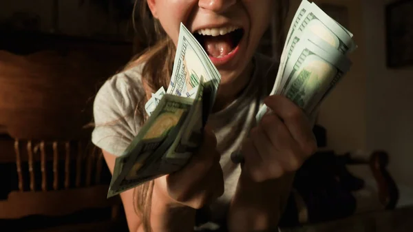 Mutlu başarılı ev hanımı kameraya gülümsüyor ve elinde yeni 100 dolarlık banknotlar tutuyor. Amerikan dolarına para sağlıyor. Dünya ekonomik krizi