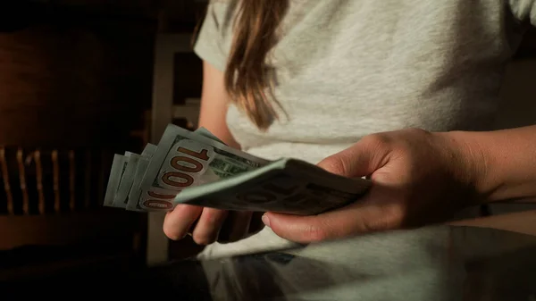 Tanımlanamayan bir kadın evde 100 dolarlık banknotları sayıyor ve kameraya Amerikan dolarları veriyor. Dünya ekonomik krizi