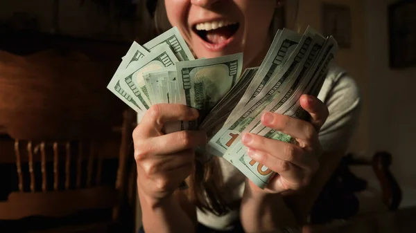 Mutlu başarılı ev hanımı kameraya gülümsüyor ve elinde yeni 100 dolarlık banknotlar tutuyor. Amerikan dolarına para sağlıyor. Dünya ekonomik krizi