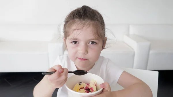 Sağlıklı, sevimli, anaokulu koyu saçlı ve kahverengi gözlü çocuk dondurma yiyor, eğleniyor. Çocukluk organik konsepti. Beyaz arkaplan