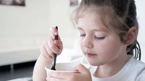 Kapatın. Sağlıklı, sevimli, anaokulu koyu saçlı çocuk dondurma yiyor, eğleniyor. Çocukluk organik konsepti. Beyaz arkaplan